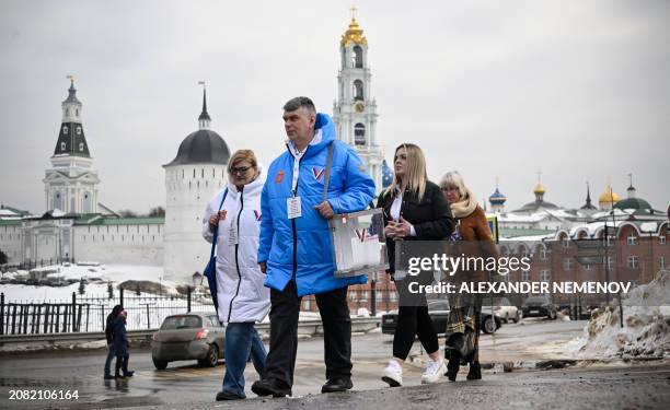 Members of a local electoral commission walk along a street to visit voters at homes during Russia's presidential election in Sergiyev Posad, some 75...