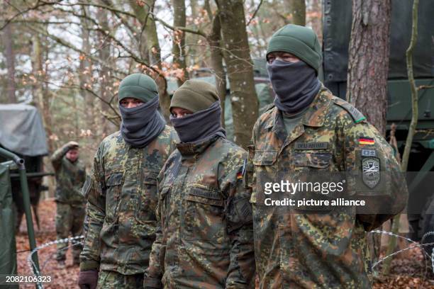 March 2024, Bavaria, Hohenfels: Two male and one female soldier of the 41st Armored Infantry Brigade stand in the forest during the military exercise...