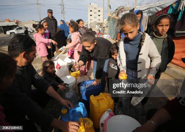 Palestinian children wait with bottles in line to get water amid clean water and food crisis from mobile storages of charities as they have limited...