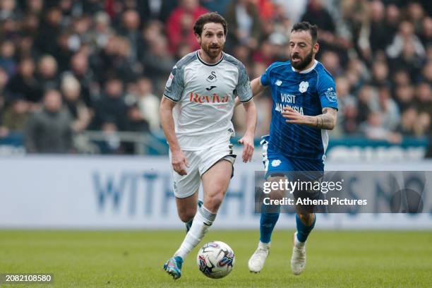 Joe Allen of Swansea City is chased by Manolis Siopis of Cardiff City during the Sky Bet Championship match between Swansea City and Cardiff City at...