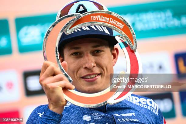 Alpecin-Deceuninck's Belgian rider Jasper Philipsen celebrates with the trophy on the podium after winning the 115th Milan-SanRemo one-day classic...