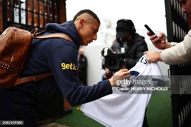 Tottenham Hotspur's Brazilian striker Richarlison signs a shirt for a fan as he arrives for the English Premier League football match between Fulham...