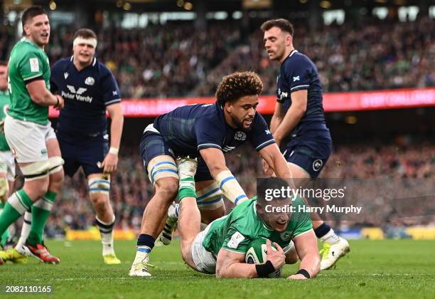 Dublin , Ireland - 16 March 2024; Dan Sheehan of Ireland dives over to score his side's first try despite the efforts of Andy Christie of Scotland...