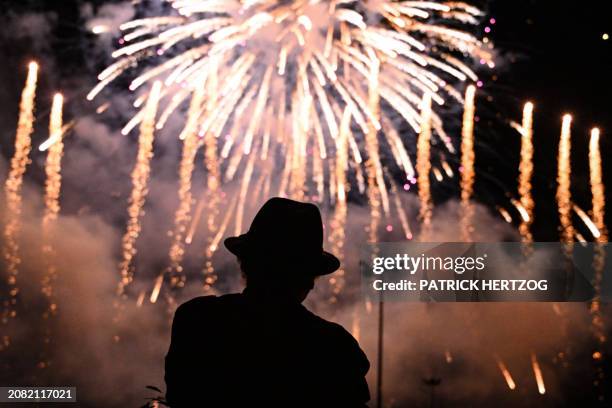 Silhouetted person watches fireworks during the opening ceremony of "Montbeliard Capitale francaise de la Culture 2024" , in Montbeliard, eastern...