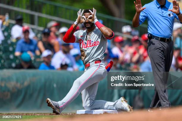 Philadelphia Phillies outfielder Johan Rojas makes goggles with his hands on third base as he celebrates hitting a triple during an MLB spring...