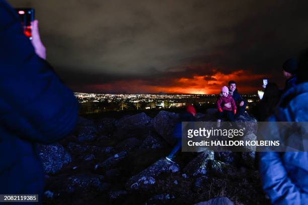 People on the outskirts of Reykjavik take pictures and selfies with the orange coloured sky as molten lava flows out from a fissure on the Reykjanes...