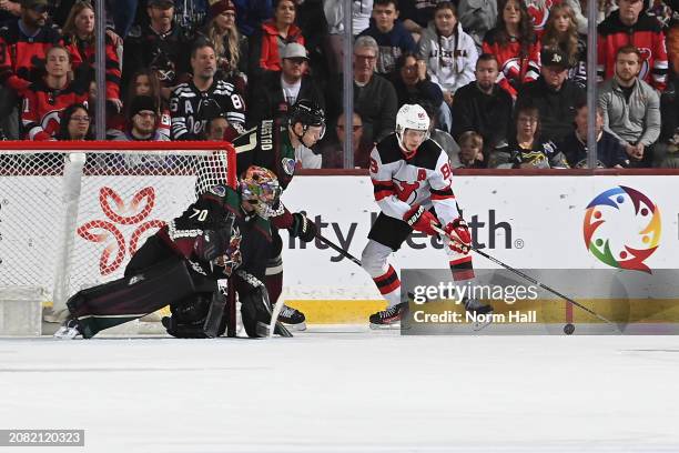 Karel Vejmelka of the Arizona Coyotes gets ready to make a save as teammate Nick Bjugstad defends Jack Hughes of the New Jersey Devils during the...