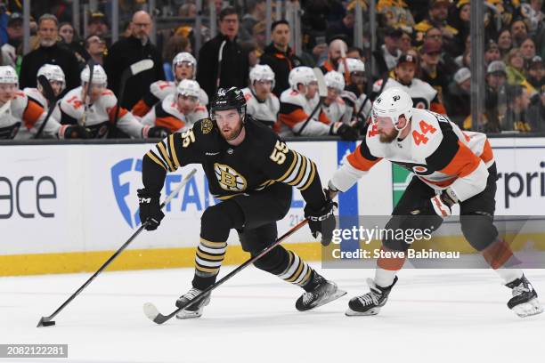 Justin Brazeau of the Boston Bruins skates with the puck against Nicolas Deslauriers of the Philadelphia Flyers at the TD Garden on March 16, 2024 in...