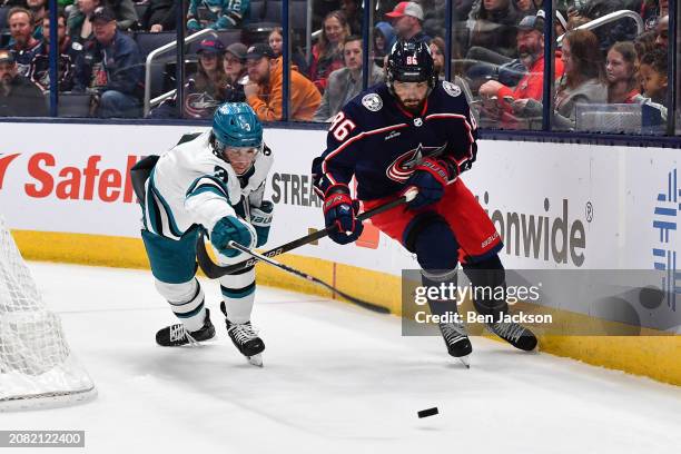 Henry Thrun of the San Jose Sharks and Kirill Marchenko of the Columbus Blue Jackets skate after a loose puck during the first period of a game at...