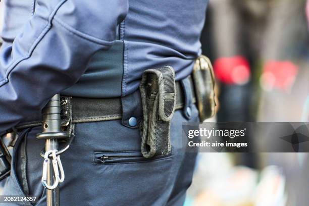close-up side view of the belt of an armed police officer standing on the city streets - cuerpo de policía fotografías e imágenes de stock