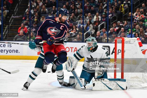 Shot deflects off Boone Jenner of the Columbus Blue Jackets as goaltender Magnus Chrona of the San Jose Sharks defends the net during the third...