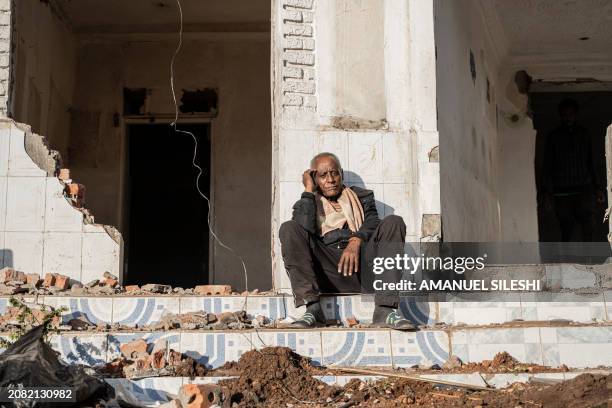 Man sits among the rubbles of a house during a planned demolition in the historical Piazza neighbourhood of Addis Ababa on March 17, 2024. The city...