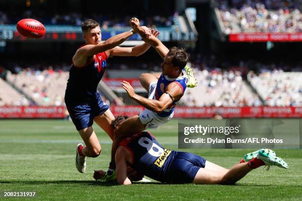 Lachlan McNeil of the Bulldogs, Blake Howes of the Demons and Jake Lever of the Demons compete for the ball during the 2024 AFL Round 01 match...