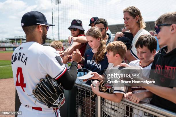 Carlos Correa of the Minnesota Twins signs autographs for fans during a spring training game against the St. Louis Cardinals on March 13, 2024 at the...
