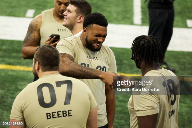 Blake Fisher #OL20 of Notre Dame shakes hands with Penn State offensive lineman Olu Fashanu during the NFL Scouting Combine at Lucas Oil Stadium on...