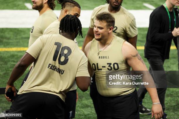 Olu Fashanu #OL18 of Penn State congratulates Garret Greenfield #OL30 of South Dakota State during the NFL Scouting Combine at Lucas Oil Stadium on...