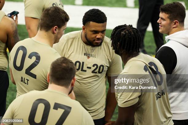 Blake Fisher #OL20 of Notre Dame reacts with Penn State offensive lineman Olu Fashanu during the NFL Scouting Combine at Lucas Oil Stadium on March...