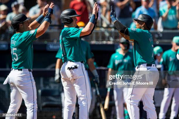 Jorge Polanco of the Seattle Mariners high fives Dylan Moore and Michael Papierski after hitting a home run during the spring training game against...