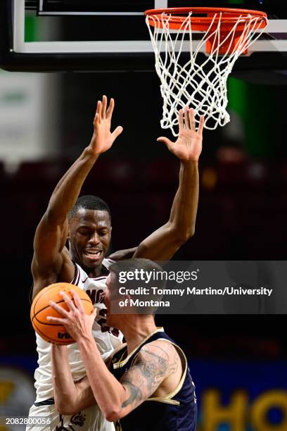 Laolu Oke of the Montana Grizzlies defends the rim as John Olmsted of the Montana State Bobcats looks to shoot in the first half during the Big Sky...