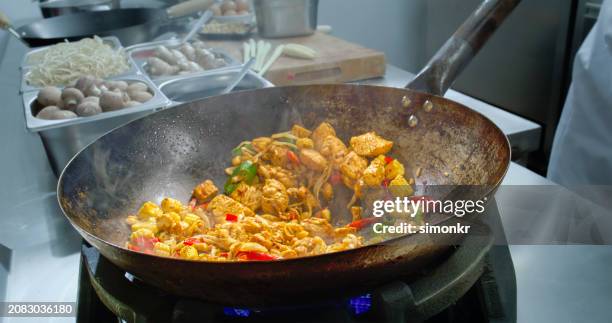 chef tossing the wok while making a stir fry and using a ladle to mix it - chef tossing fire stock-fotos und bilder