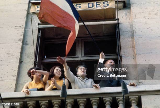 People waving a French flag from a window during a demonstration in support of General De Gaulle on the Champs-Élysées in Paris, May 30th 1968.