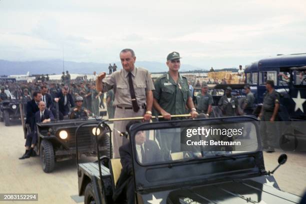 President Lyndon Johnson , standing next to General William Westmoreland on the back of a jeep, visits troops at Cam Ranh Bay in Vietnam, December...