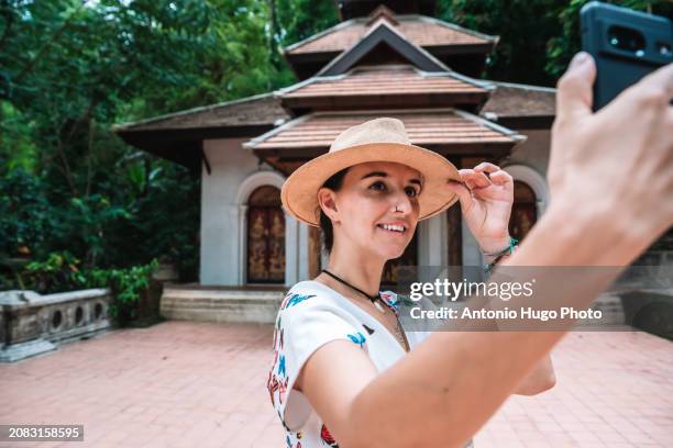 young smiling woman taking a selfie at wat phra lat mountain temple in chang mai - art of the vintage selfie stockfoto's en -beelden