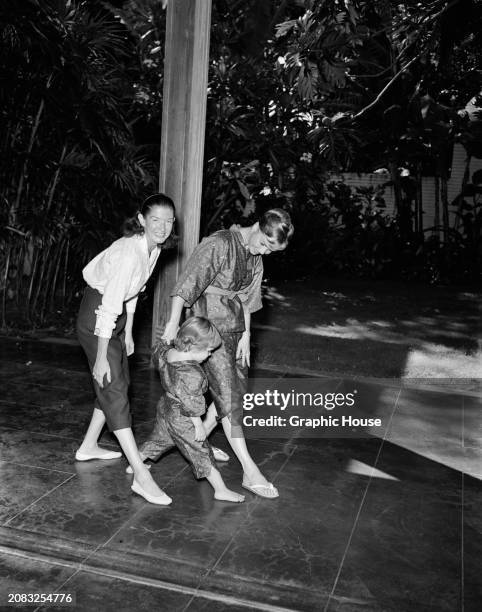 Mother Debbie Reynolds and daughter Carrie Fisher, wearing matching outfits, learn some new dance moves with a third woman, US, circa 1959.