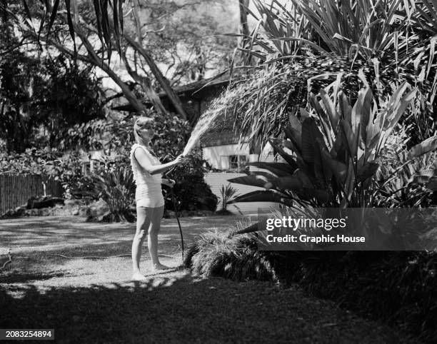 American actress, singer, and businesswoman Debbie Reynolds watering plants at home, US, circa 1959.