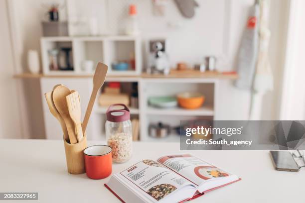 senior couple looking at the cookbook and reading recipes to cook - cookbook stock pictures, royalty-free photos & images