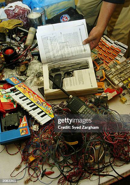 Pistol hidden in a book is displayed with bomb-making materials that were recovered during the arrest of five Islamic militants June 15, 2003 in...
