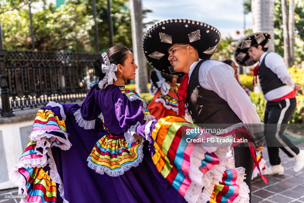 Pareja joven bailando en festival tradicional en parque público