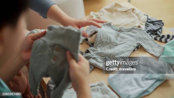 sweet asian happiness new parent couple asia cheerful pregnant woman getting ready for her new born baby preparing baby cloth and baby room with her husband - babybekleidung stock-fotos und bilder