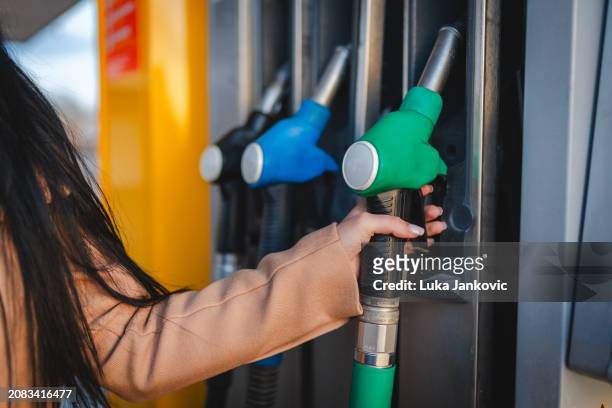 close-up of human hand holding a fuel nozzle at the gas station - hose nozzle stock pictures, royalty-free photos & images