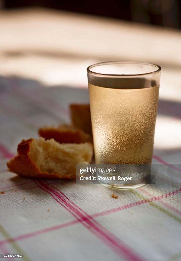 A glass of white wine and bread on a sunny table