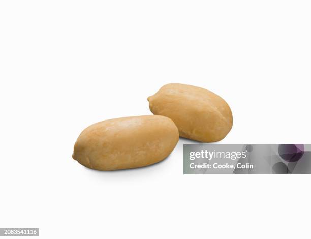 two shelled peanuts on a white surface (close-up) - shelled peanuts stock pictures, royalty-free photos & images