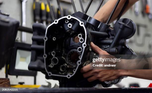 mechanic repairing the engine of a motorcycle at a garage - reserveonderdeel stockfoto's en -beelden
