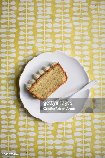 a slice of lemon and poppyseed cake with cream cheese frosting on white plate with a fork - anne faber fotografías e imágenes de stock