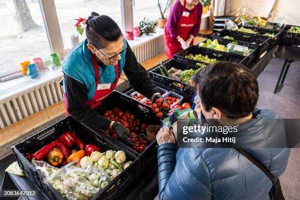 Woman picks groceries on offer at the 49th food bank of the Berliner Tafel charity on the food bank's opening day on March 14, 2024 in Berlin,...