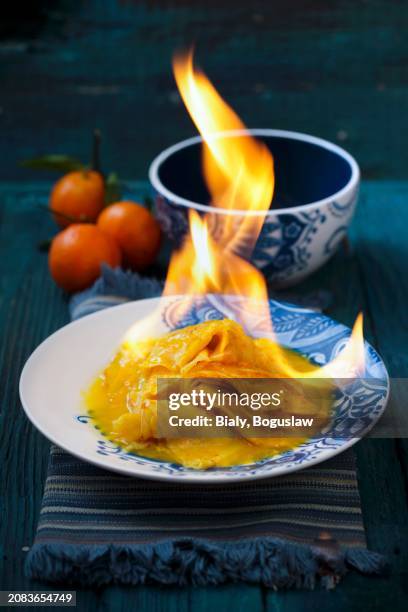 crêpe suzette being flambéed with orange syrup and orange liqueur - flambiert stock-fotos und bilder