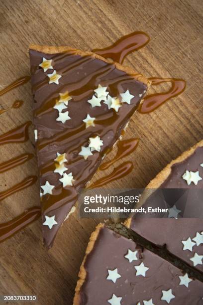 tarte au chocolat decorated with small white stars and caramel sauce on a wooden board - glace au chocolat - fotografias e filmes do acervo