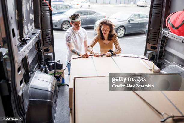 relocation preparations: young navy officer and his girlfriend load boxes into a cargo van on moving day. - offloading stock pictures, royalty-free photos & images