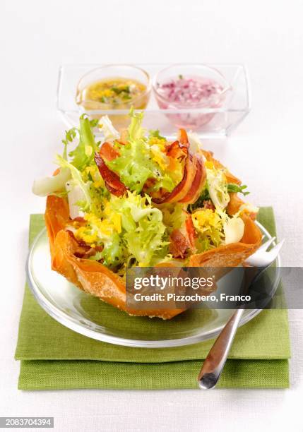 frisee lettuce with bacon, egg and two salad dressings - krulandijvie stockfoto's en -beelden