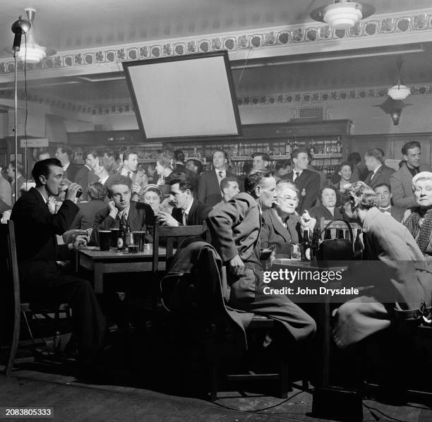Pub audience gathered for a cabaret show at the George Hotel in Slough, Berkshire, April 1956. Pub landlady Peggy Leslie, a dancer, staged...
