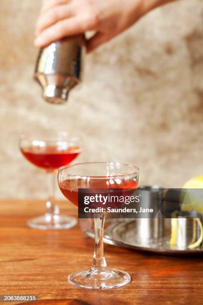 a cocktail being poured from a shaker into glasses - glazier stock pictures, royalty-free photos & images