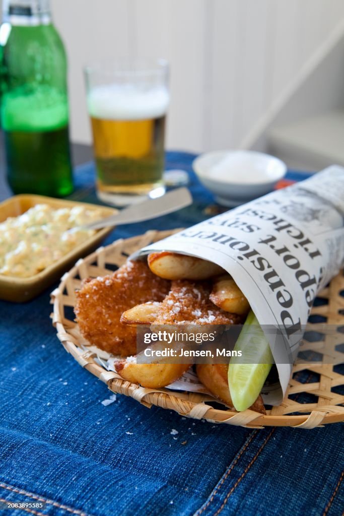 Breaded chicken strips with french fries in newspaper bag