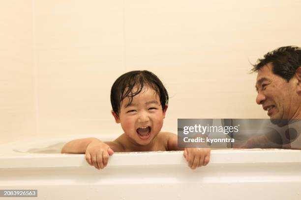 child enjoying a bath with his family - old man bathtub stock pictures, royalty-free photos & images