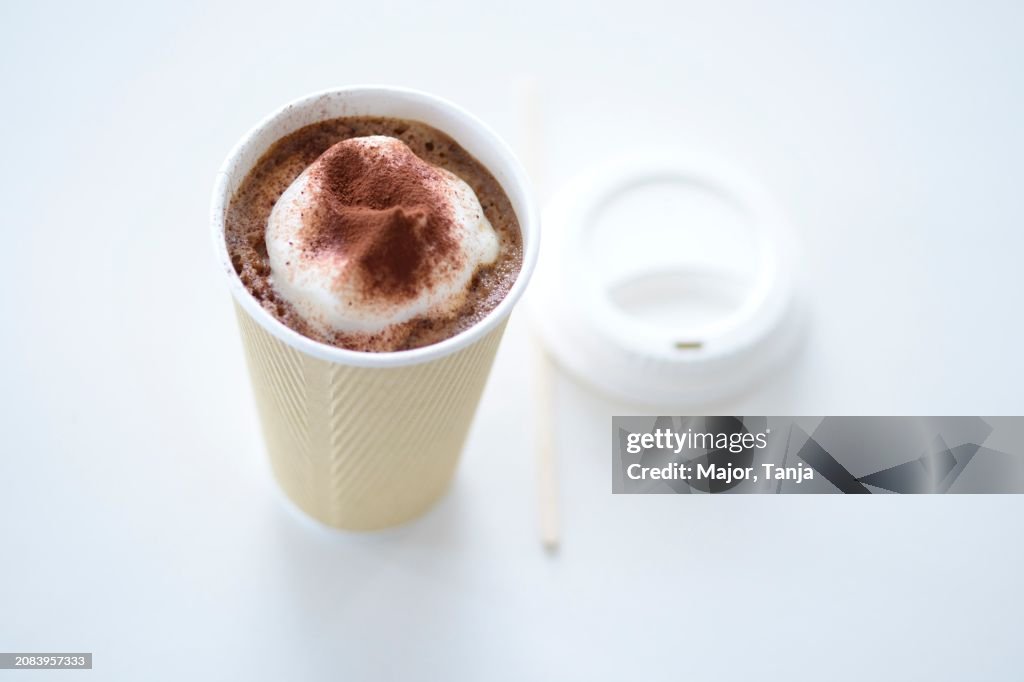 A mug of cocoa with cream in a take away cup