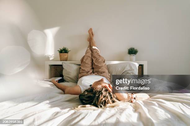 portrait of a woman with book lying on the bed - krampfadern stock-fotos und bilder