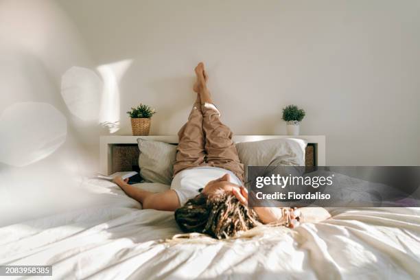 portrait of a woman with book lying on the bed - woman legs up bed stock pictures, royalty-free photos & images